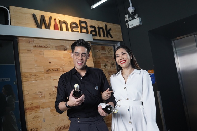 young couple happily came out of a wine storage room holding wines 