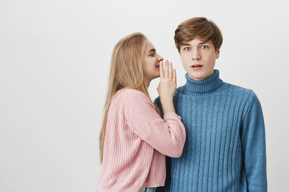 a woman shares a secret with a man